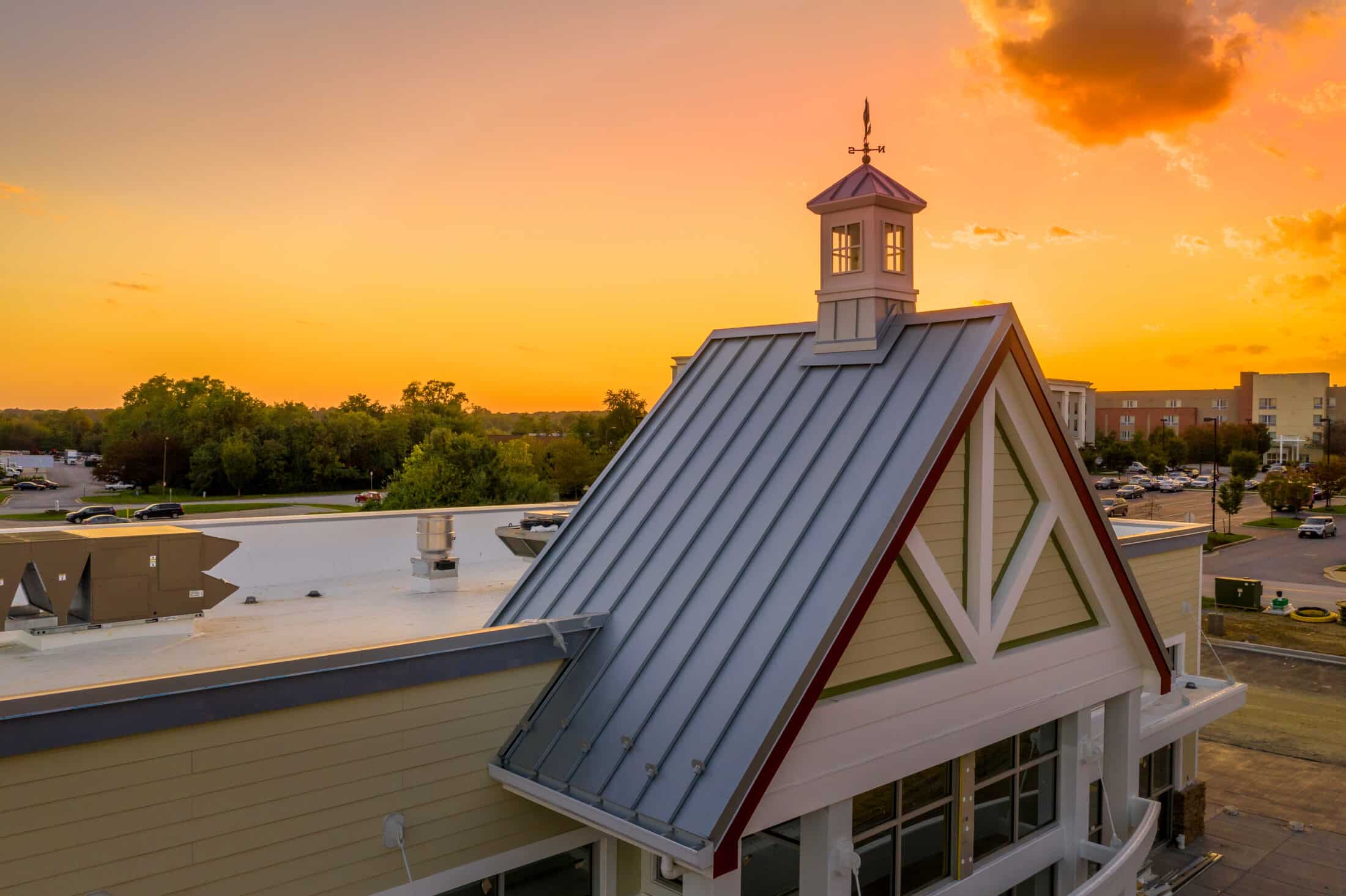 Weather vane cupola on a gable roof with colorful sunset sky